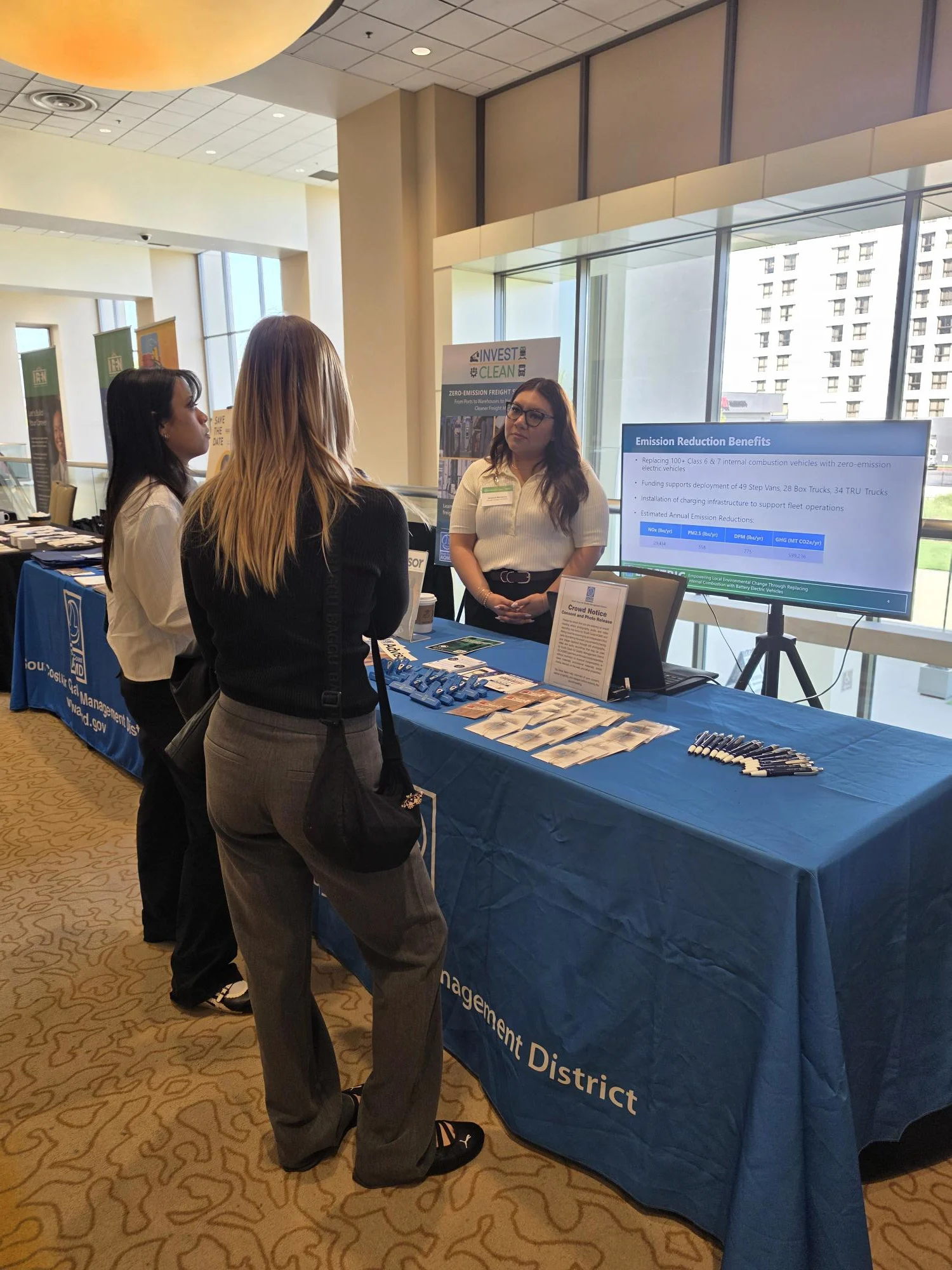 Attendee at a South Coast AQMD booth with INVEST CLEAN and clean-air promotional materials
